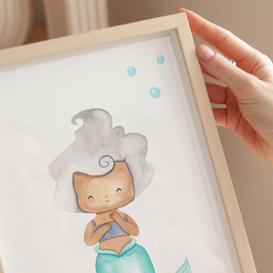 Poster Meerjungfrau silber A3 & A4: Eine Hand hält ein illustriertes Bild einer Meerjungfrau, ideal als Kinderzimmerdeko oder Geschenk, gedruckt auf festem Naturpapier.