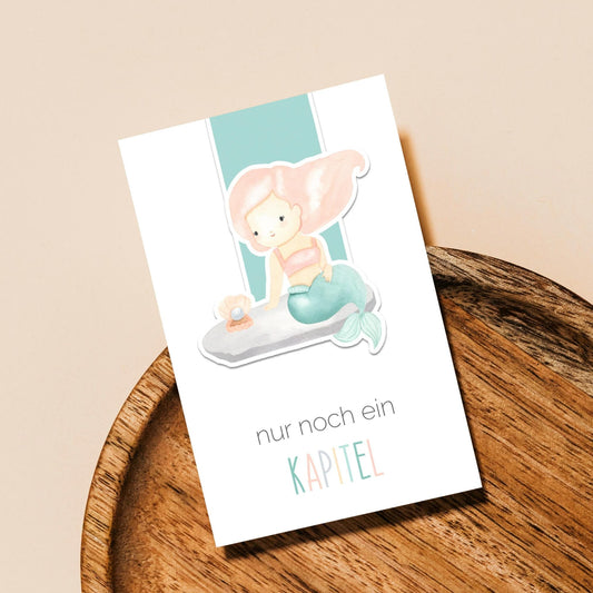 Magnetisches Lesezeichen Meerjungfrau: Handgemaltes Meerjungfrau-Motiv, cartoonartig auf hochwertigem Papier, ideal für Buchliebhaberinnen. Enthält Magnete für sicheren Halt an Buchseiten.