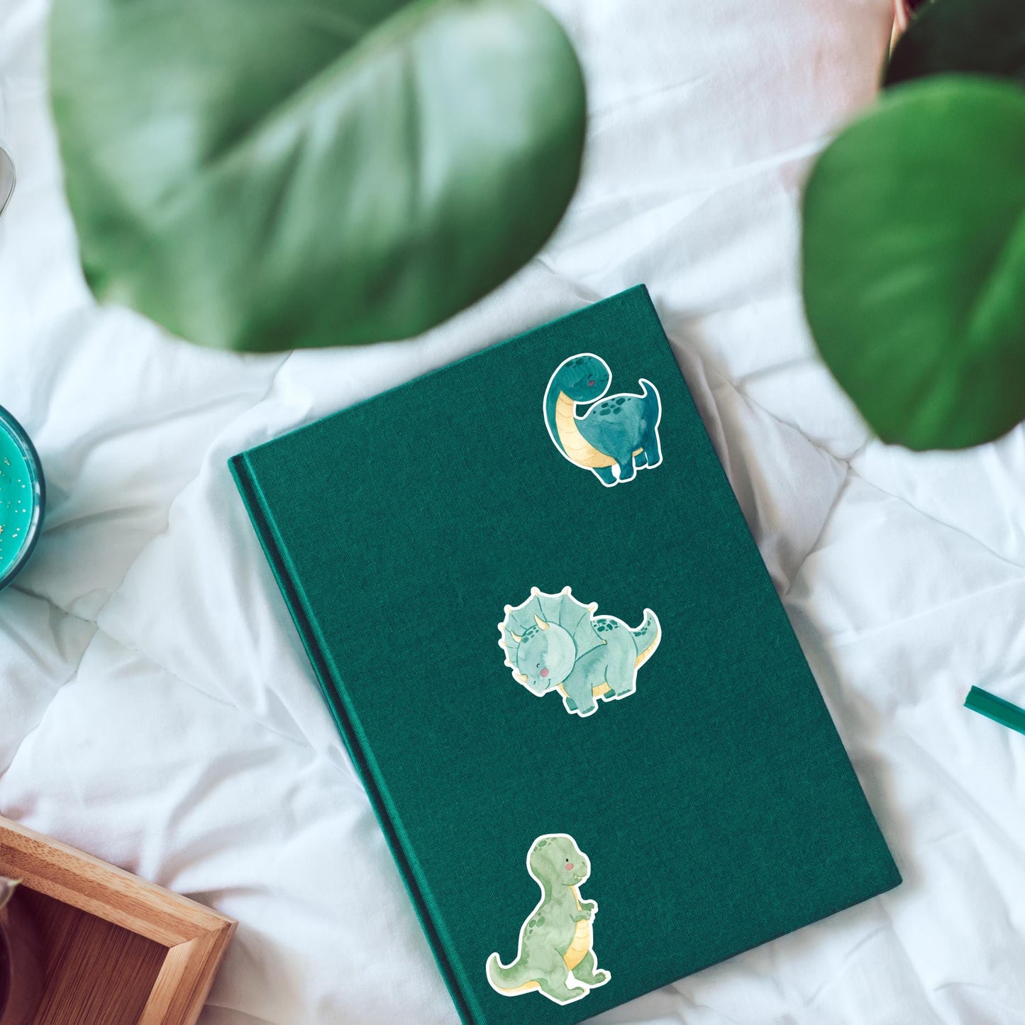Sticker Dinosaurier Dreizack: Ein grünes Buch mit handgemaltem Dino-Sticker, ideal für Bullet Journals oder Bastelprojekte, spritzfest und langlebig.