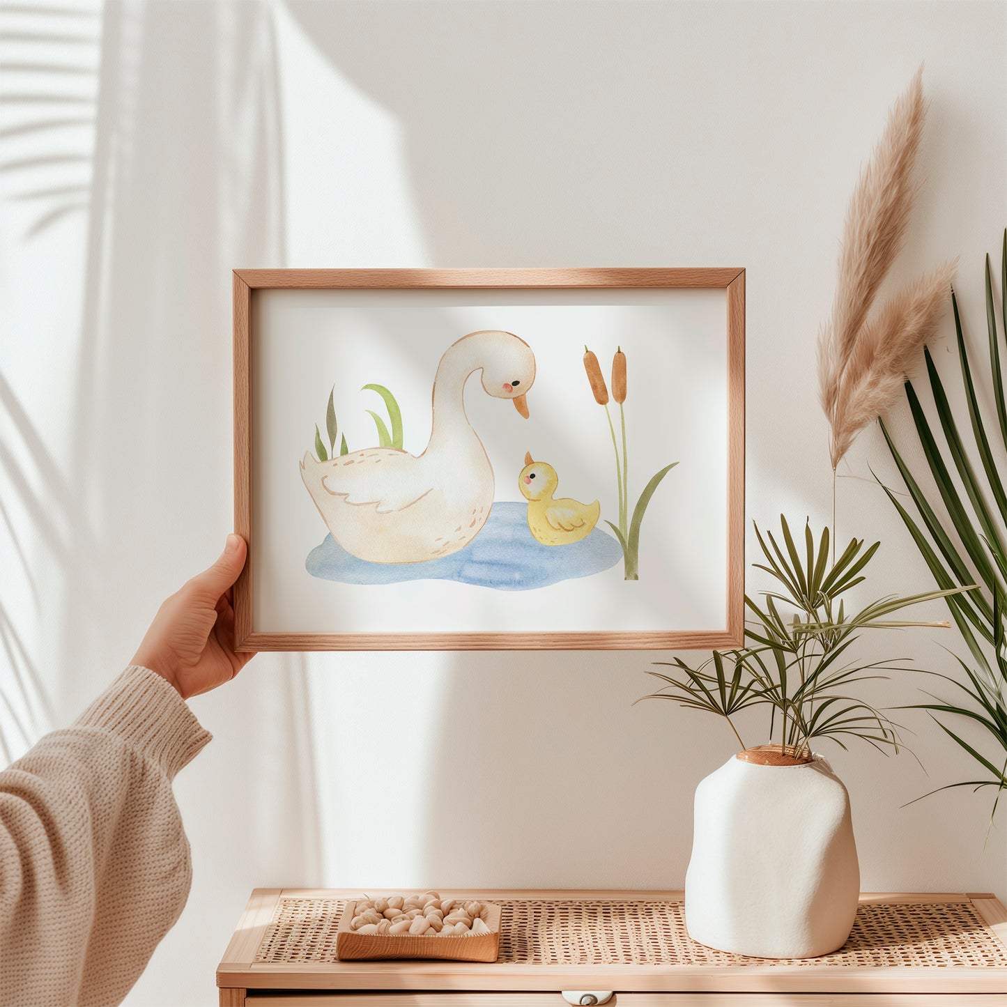 Person hält Poster Ententeich A4 & A3: Eine detaillierte Illustration einer Ente mit einem Entenküken, ideal als Kinderzimmerdekoration. Hochwertiger Druck auf 300g Naturpapier, erhältlich in zwei Größen.