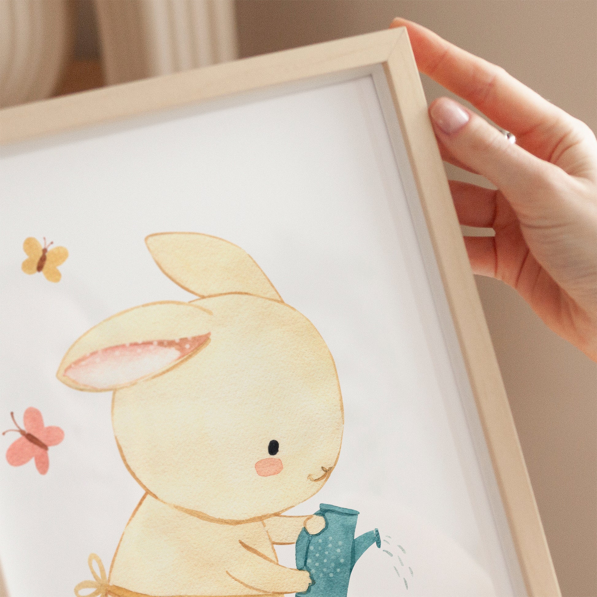 Person hält Poster Hase im Garten A4 & A3: Aquarell Hase gießt Blumen. Perfekt als fröhliche Kinderzimmerdeko oder Geschenk, auf hochwertigem Naturpapier gedruckt.
