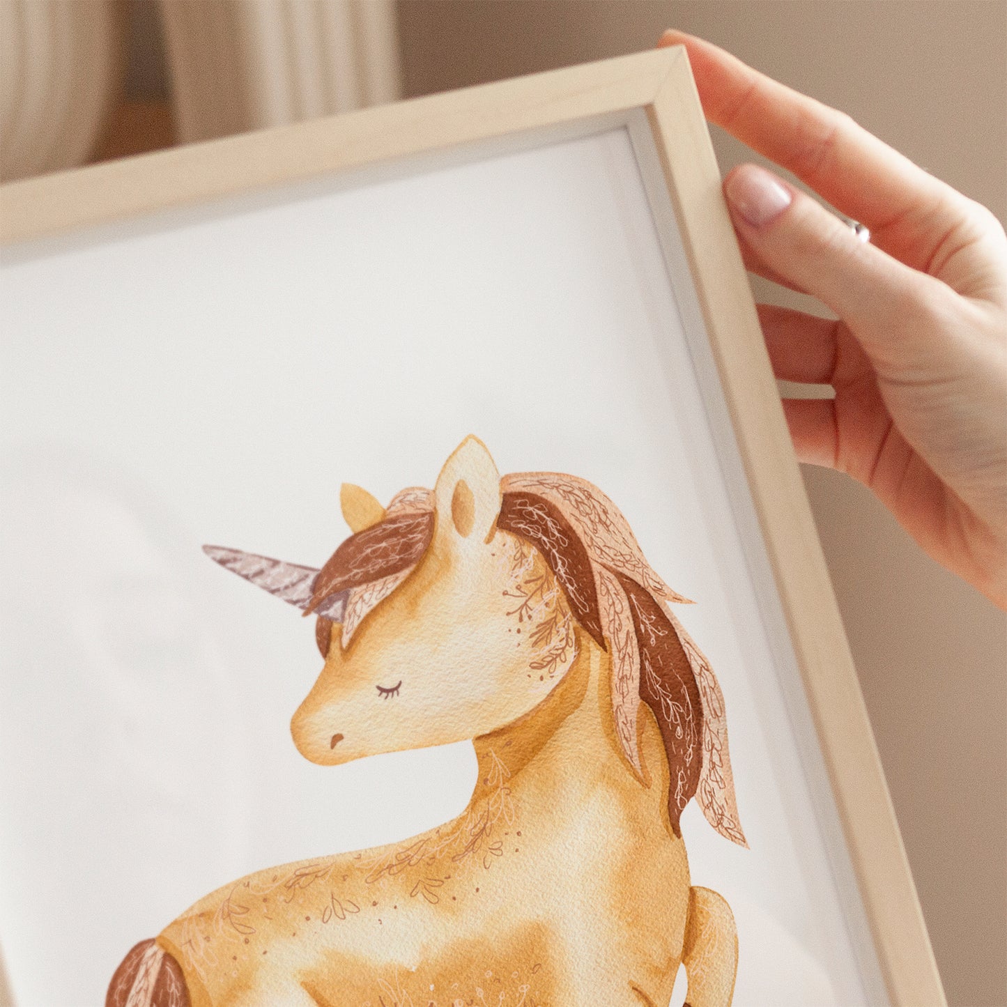 Person hält Poster Einhorn Boho A4 & A3: Detailreiche handgezeichnete Einhorn Illustration im Aquarellstil auf hochwertigem, mattem 300g Naturpapier, ideal für Kinderzimmer.