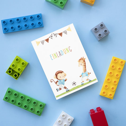 Einladung Kindergeburtstag Fußball A6: Karte mit bunten Buchstaben, Bunting-Flaggen, und Aquarell-Tieren im Fußballthema, umgeben von bunten Bauklötzen.