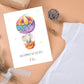 Personalisierte Geburtskarte Elefant & Heißluftballon A6, zeigt Baby-Elefant im Ballon mit Willkommen auf der Welt und Name Felix, umgeben von Baby-Accessoires.