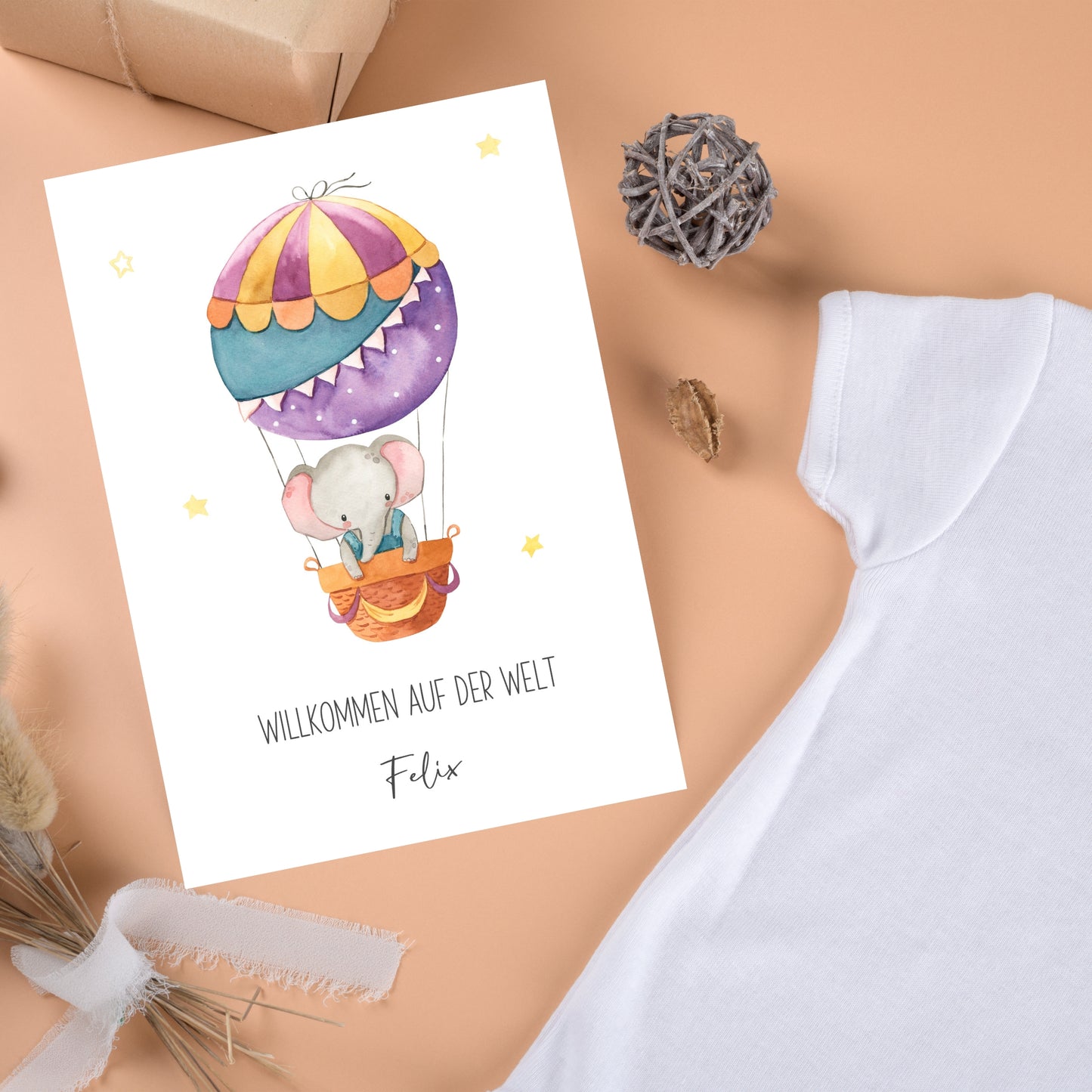 Personalisierte Geburtskarte Elefant & Heißluftballon A6, zeigt Baby-Elefant im Ballon mit Willkommen auf der Welt und Name Felix, umgeben von Baby-Accessoires.