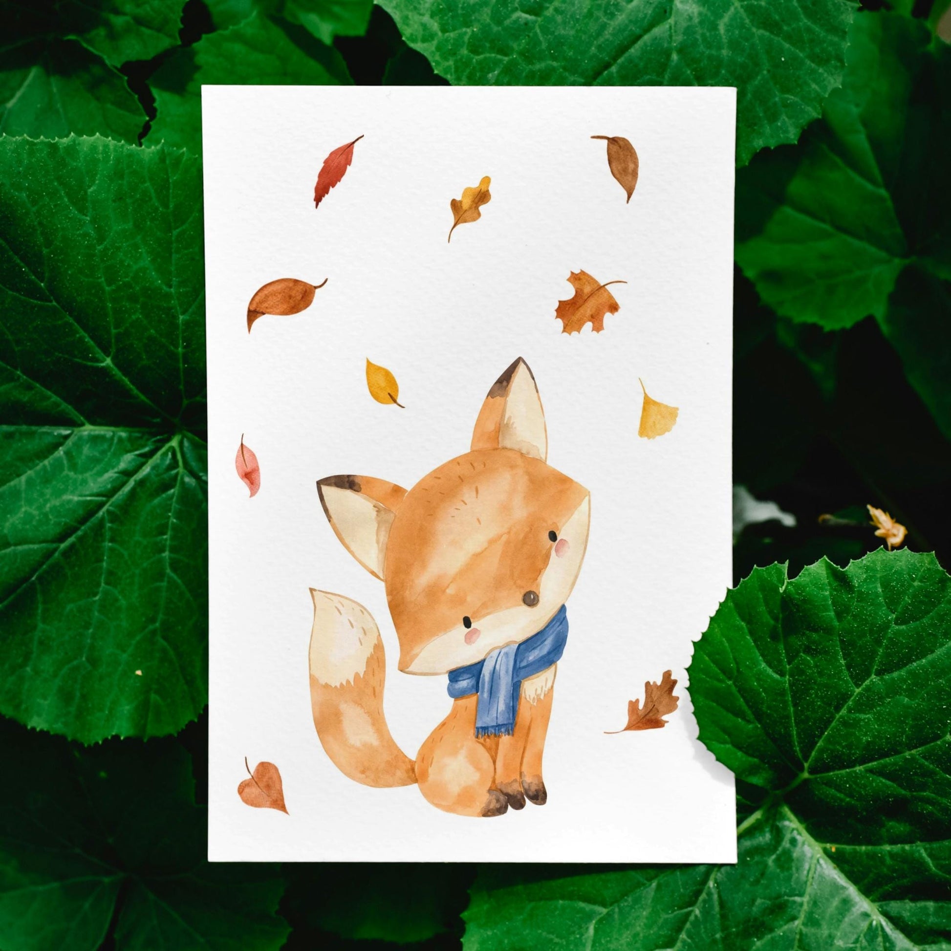 Karte Fuchs & Herbstlaub A6 zeigt einen Fuchs mit Schal und buntem Herbstlaub, gedruckt auf hochwertigem, mattem Naturpapier. Perfekt für Grüße oder Dekoration.
