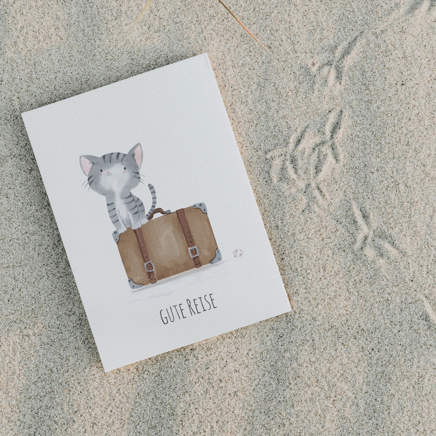 Postkarte Karte Gute Reise Katze A6: Katze auf einem Koffer sitzend, daneben ein Ball, Text: Gute Reise. Auf hochwertigem, mattem Naturpapier gedruckt.