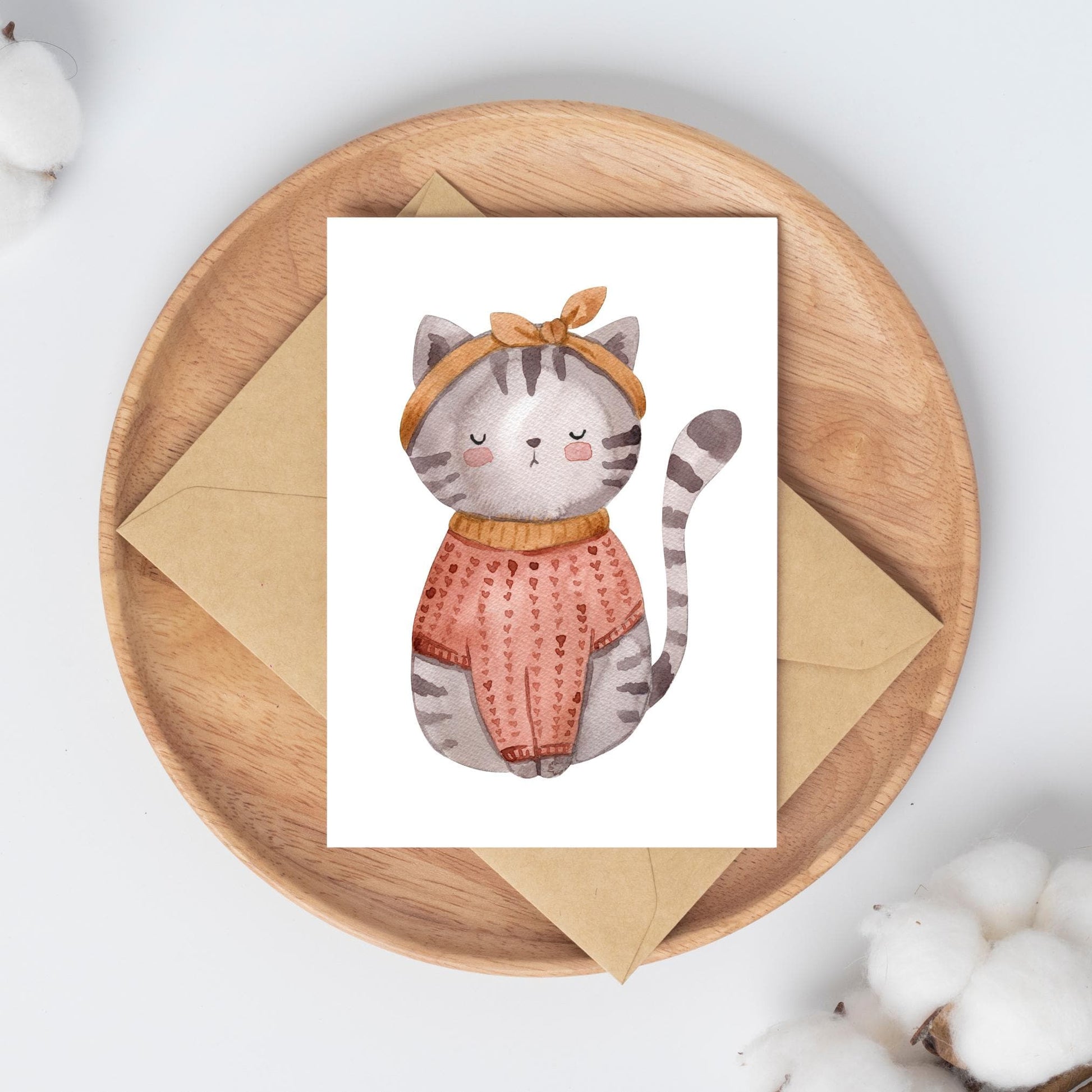 Karte Katze Vintage A6: Handgezeichnete Karte mit einer Katze in einem Pullover und mit Schleife, auf einer Holzplatte präsentiert. Ideal als Gruß- oder Geburtstagskarte.