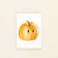 Poster für Kinder mit einer Illustration von einem fröhlichen orangefarbenen Kürbis mit lächelndem Gesicht. Das Kinderbild hängt mit einer an Posterleiste an der Wand. Perfekt für Herbst-Dekoration im Kinderzimmer.