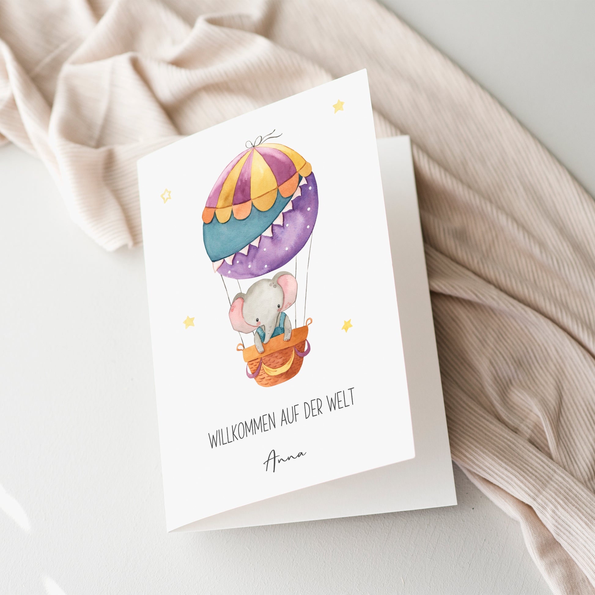 Personalisierte Geburtskarte Elefant & Heißluftballon A6 mit Aquarell-Elefant im Heißluftballon und Willkommen auf der Welt Text, inklusive Namen.