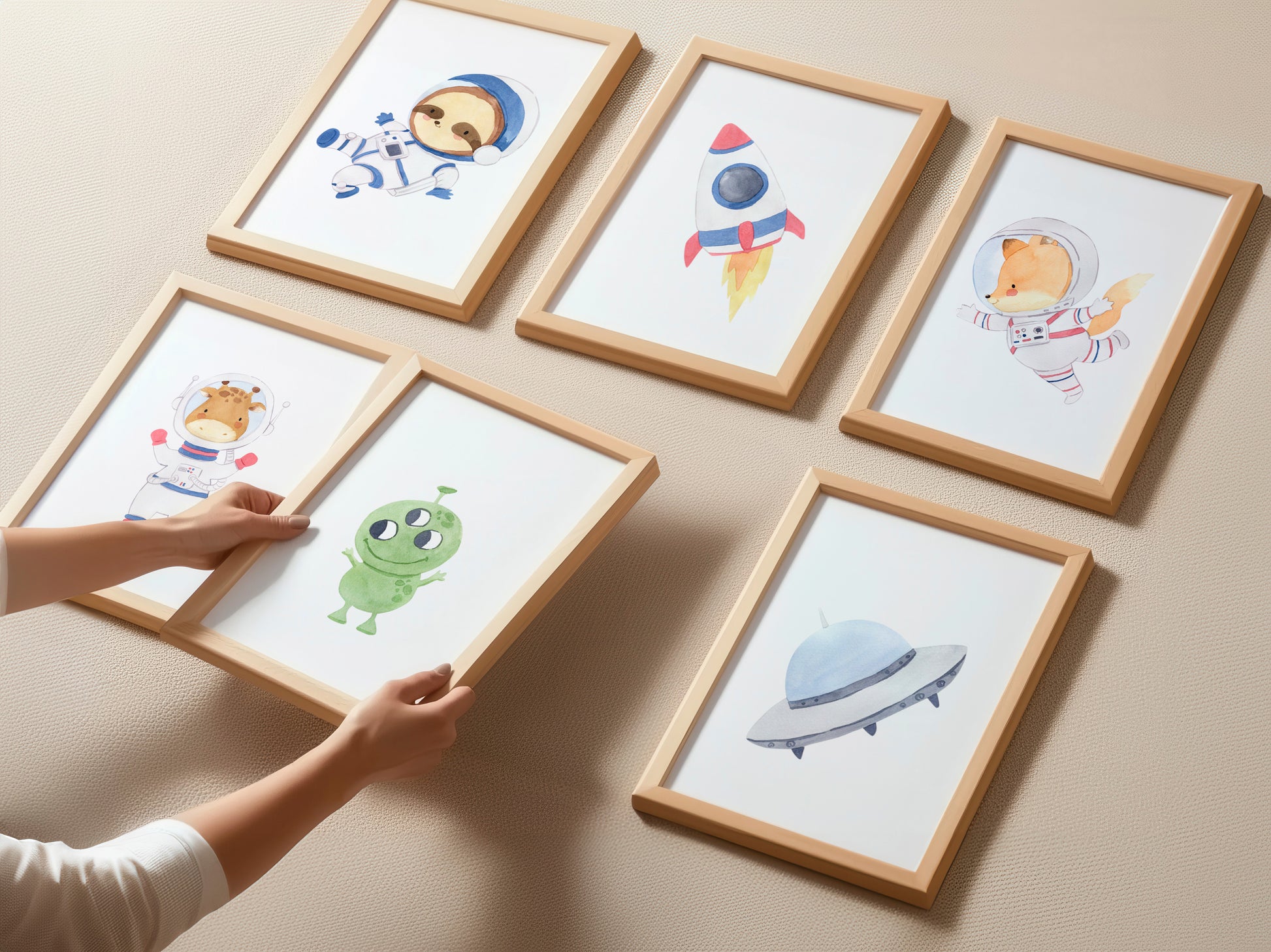 Posterset Astronauten A3 & A4: Sechs Holzrahmen mit Weltraum-Aquarellmotiven, darunter Astronauten-Tiere und UFO, an einer strukturierten Wand, geeignet für Kinderzimmer.