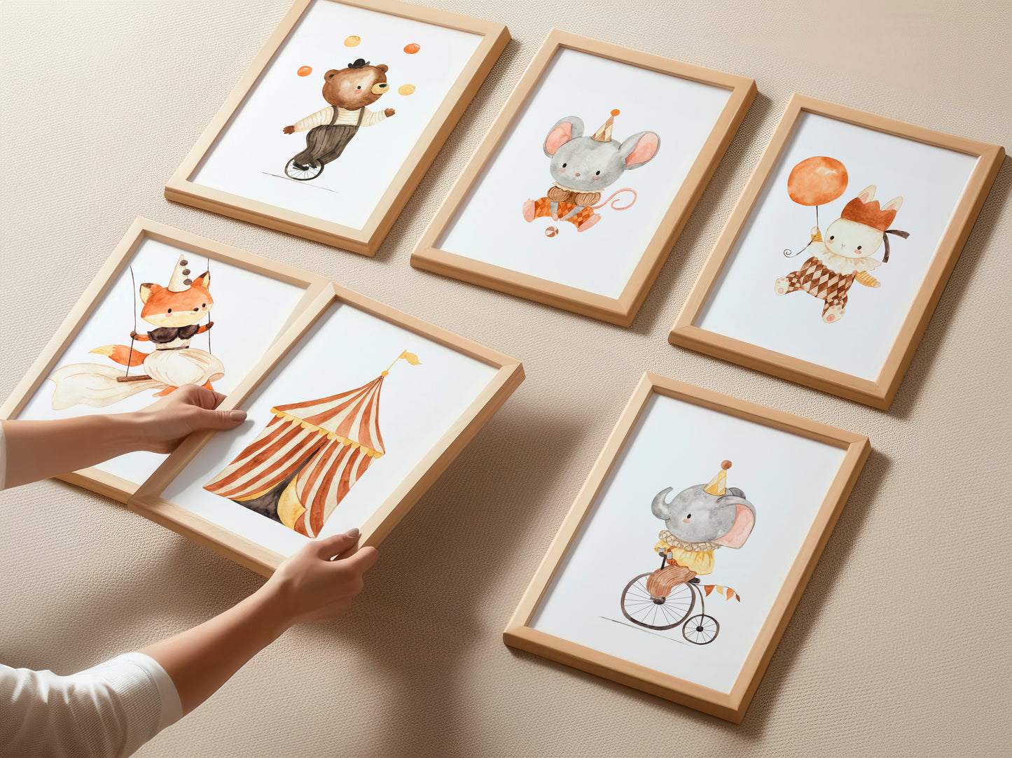 Posterset Zirkus A3 & A4: Sechs Holzrahmen mit Aquarell-Illustrationen von Zirkustieren und Zelt. Hände arrangieren Fuchs- und Zeltbilder. Ideal für Kinderzimmerdekoration.