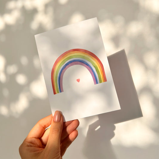 Hand hält Karte Regenbogen mit Herz A6, handbemalt auf hochwertigem, mattem Naturpapier. Perfekt für Grüße oder Glückwünsche. Größe A6, Rückseite beschreibbar.
