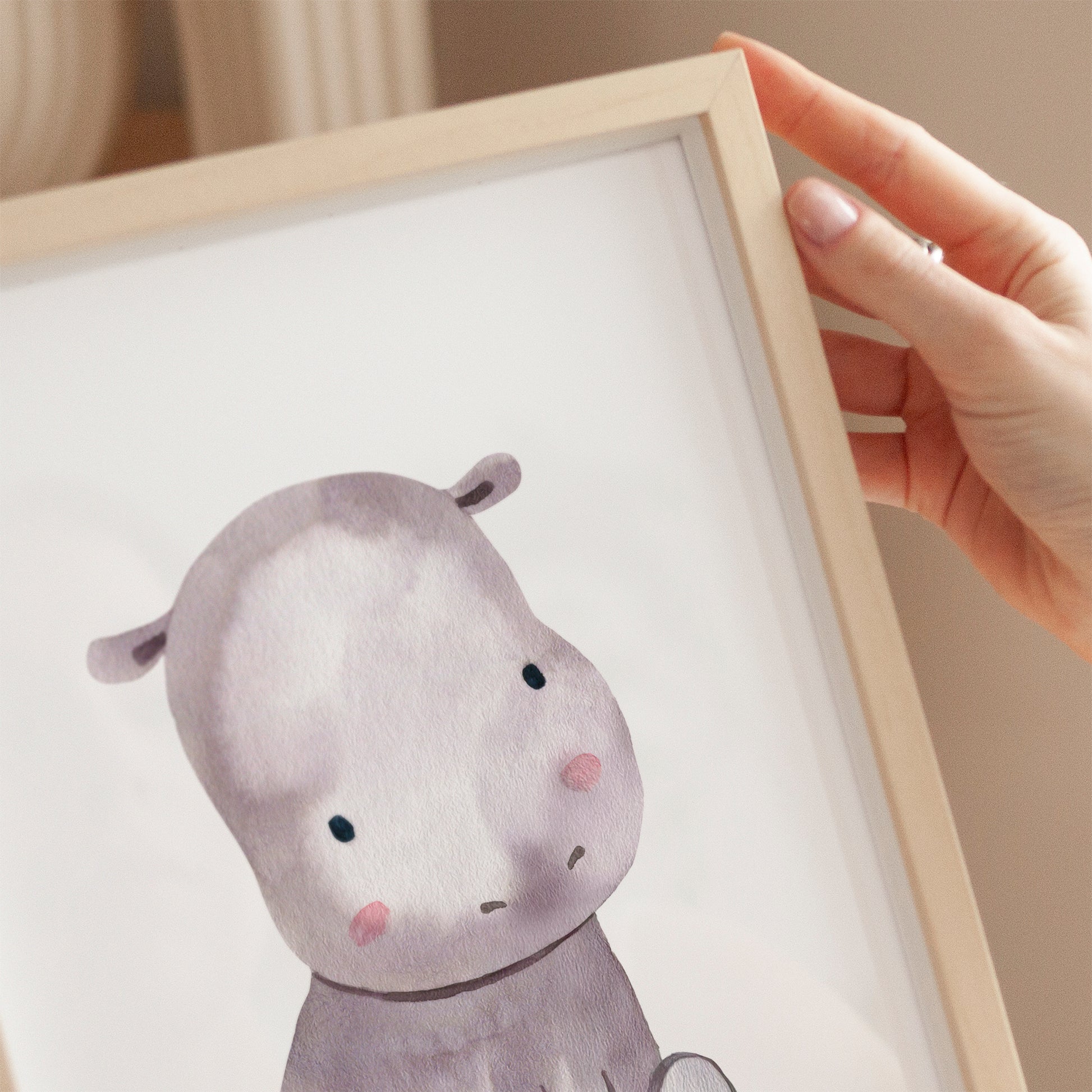 Poster Flusspferd A3 & A4 zeigt eine Hand, die ein niedliches Flusspferd-Aquarell hält, perfekt als Kinderzimmerdeko oder Geschenk für kleine Abenteurer.