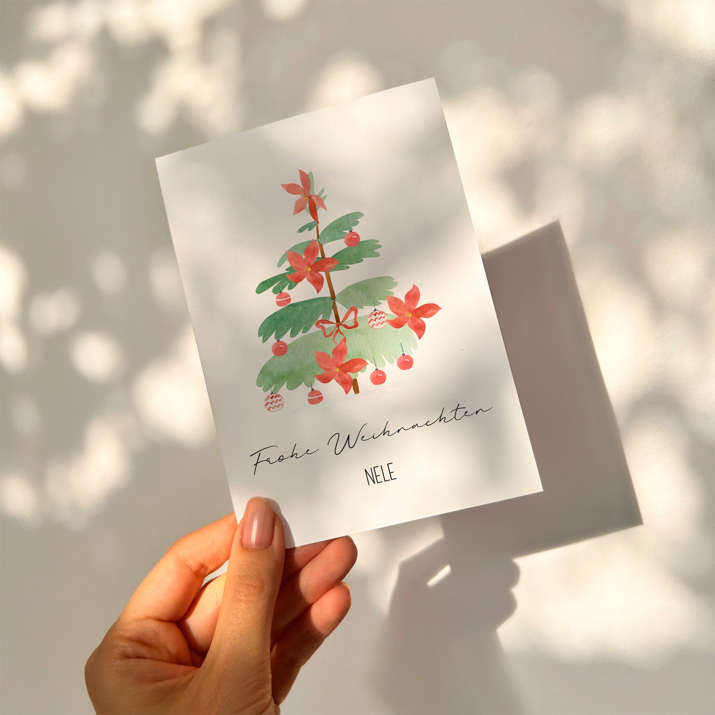 Person hält eine Personalisierte Weihnachtskarte Weihnachtsbaum A6, mit einem Weihnachtsbaum und Frohe Weihnachten darauf. Karte personalisierbar mit Namen, ideal für Geschenke.
