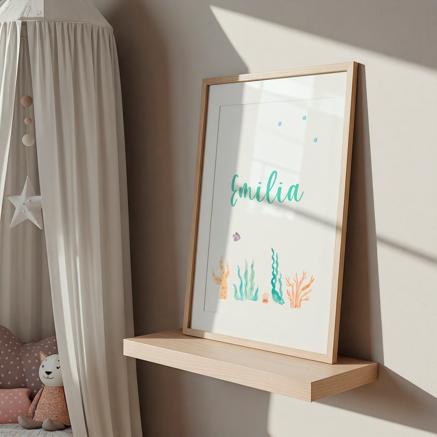 Personalisierter Namensposter-Teil eines 3er Sets: Meerjungfrau, A3 & A4, auf leichtem Regal im Kinderzimmer mit Emilia in grüner Kursivschrift und maritimen Motiven.