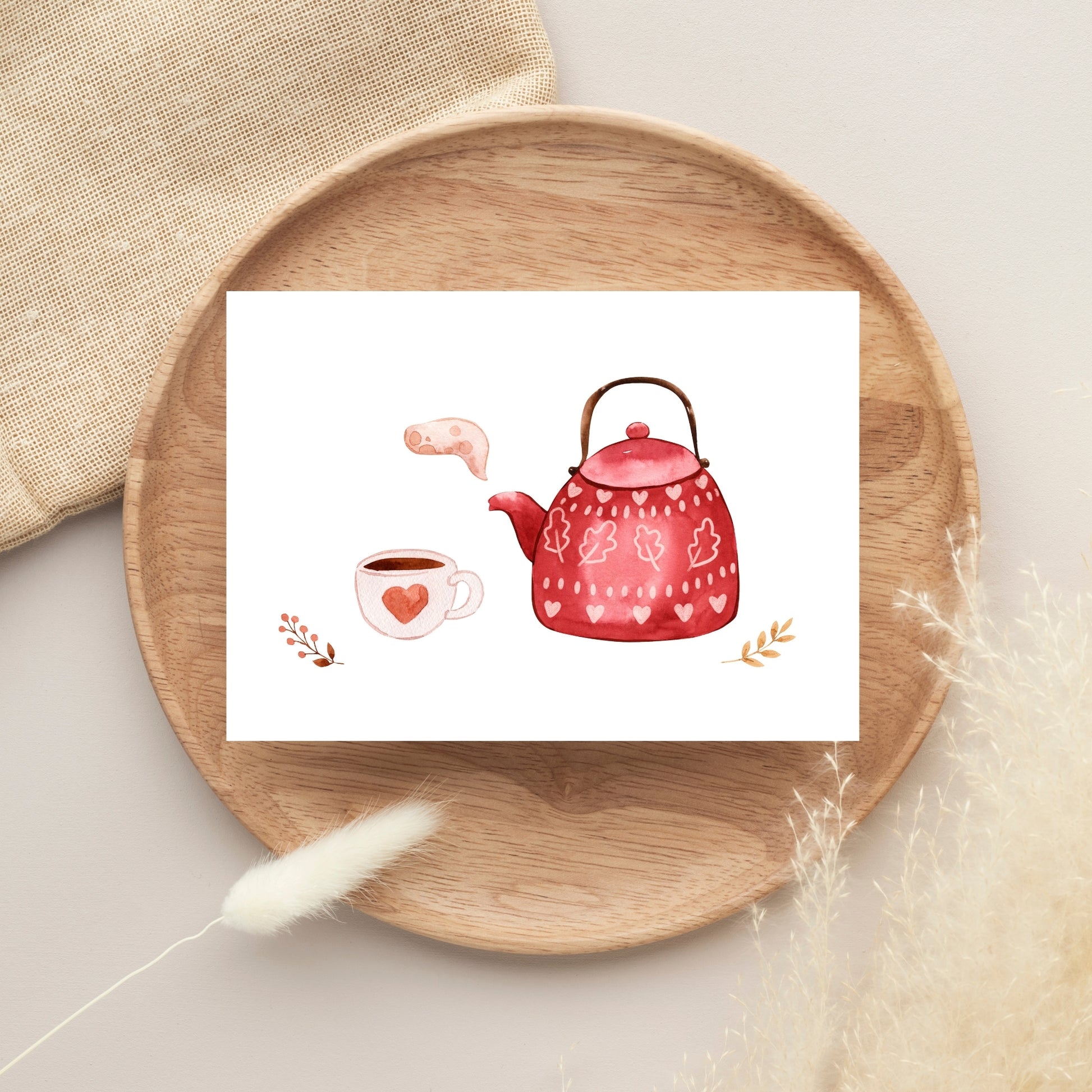 Postkarte Karte Tea Time A6 auf Holztablett, zeigt Aquarell einer roten Teekanne mit Herzen, Teetasse und Zweigen. Ideal für Einladungen oder Grüße.
