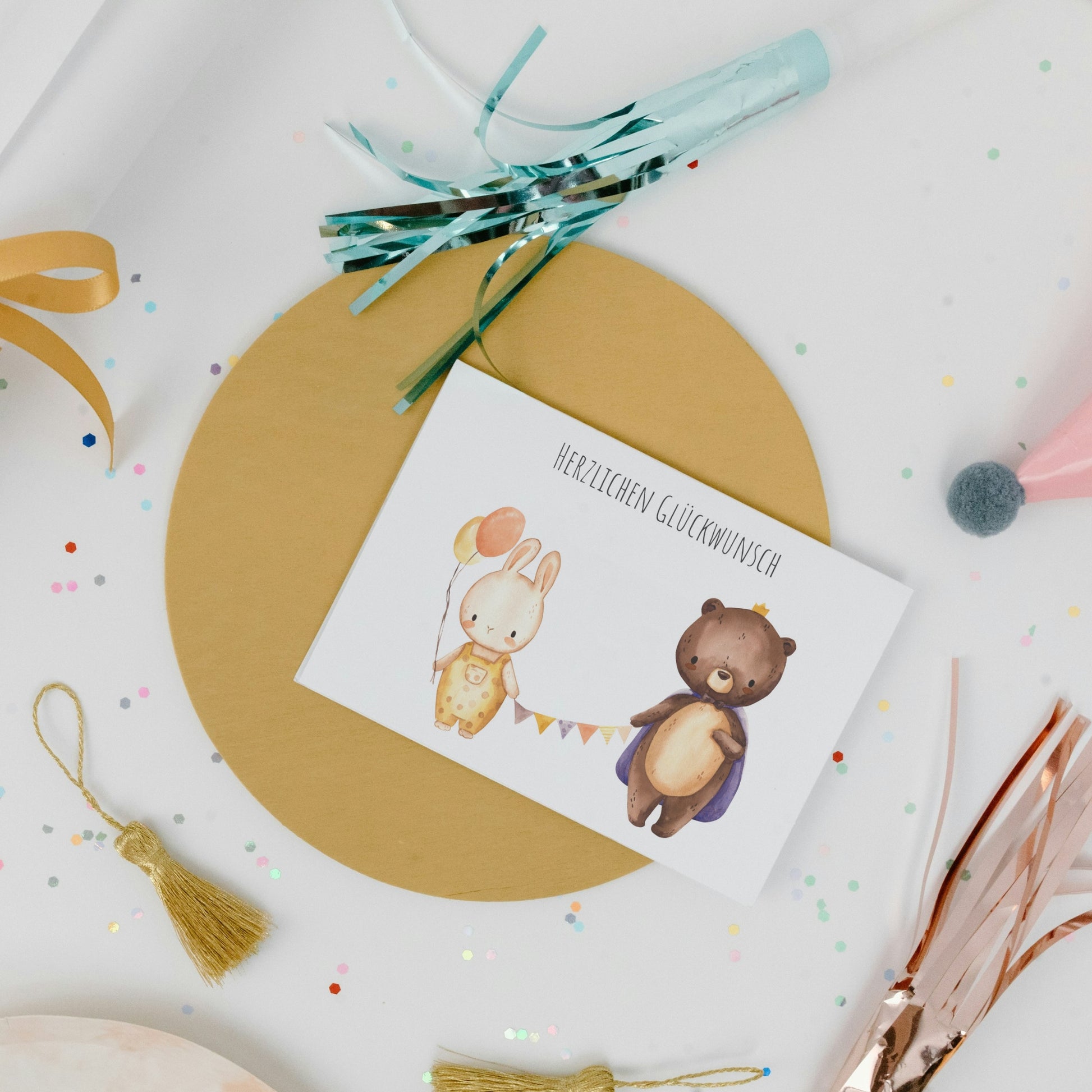 Karte Herzlichen Glückwunsch Hase & Bär A6, zeigt Aquarellhase mit Ballons und Bär mit Umhang auf Goldmatte, umgeben von Partydekorationen.