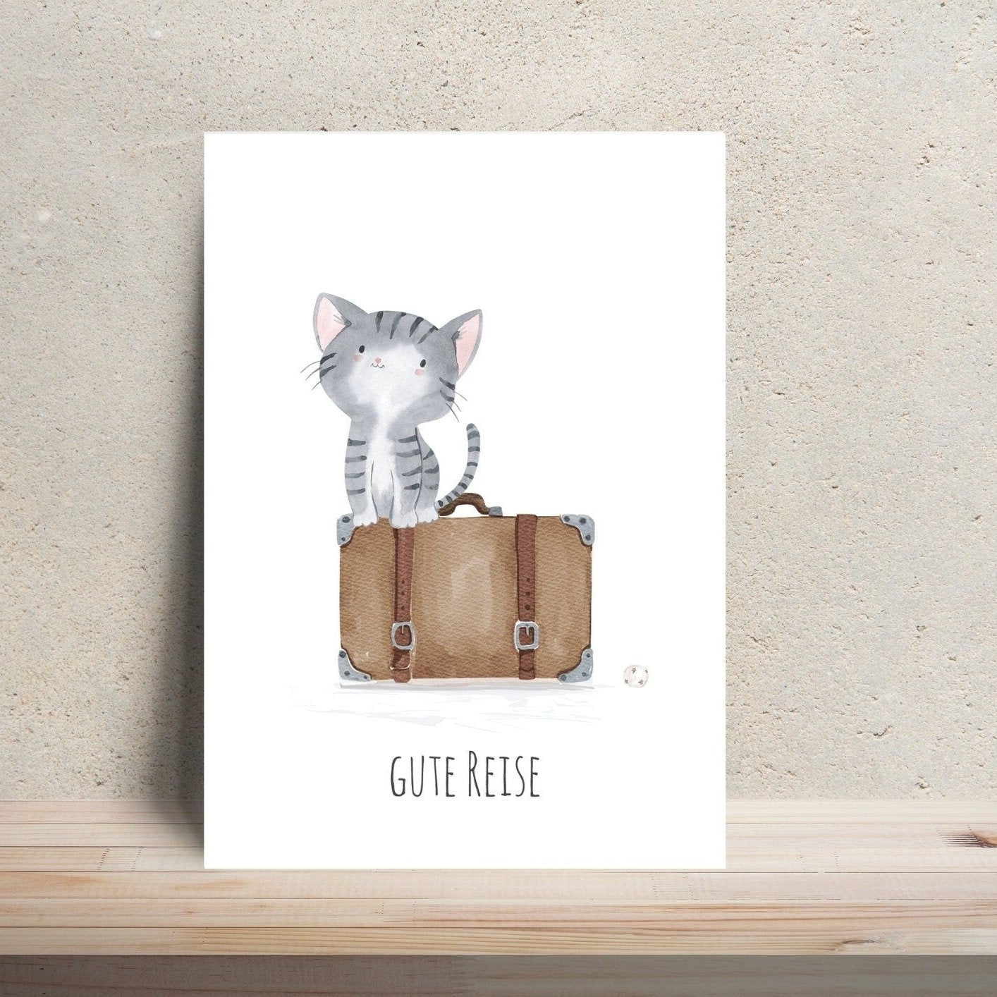 Postkarte Karte Gute Reise Katze A6: Katze auf einem Koffer sitzend, daneben ein Ball, Text: Gute Reise, auf hochwertigem, mattem Naturpapier gedruckt.