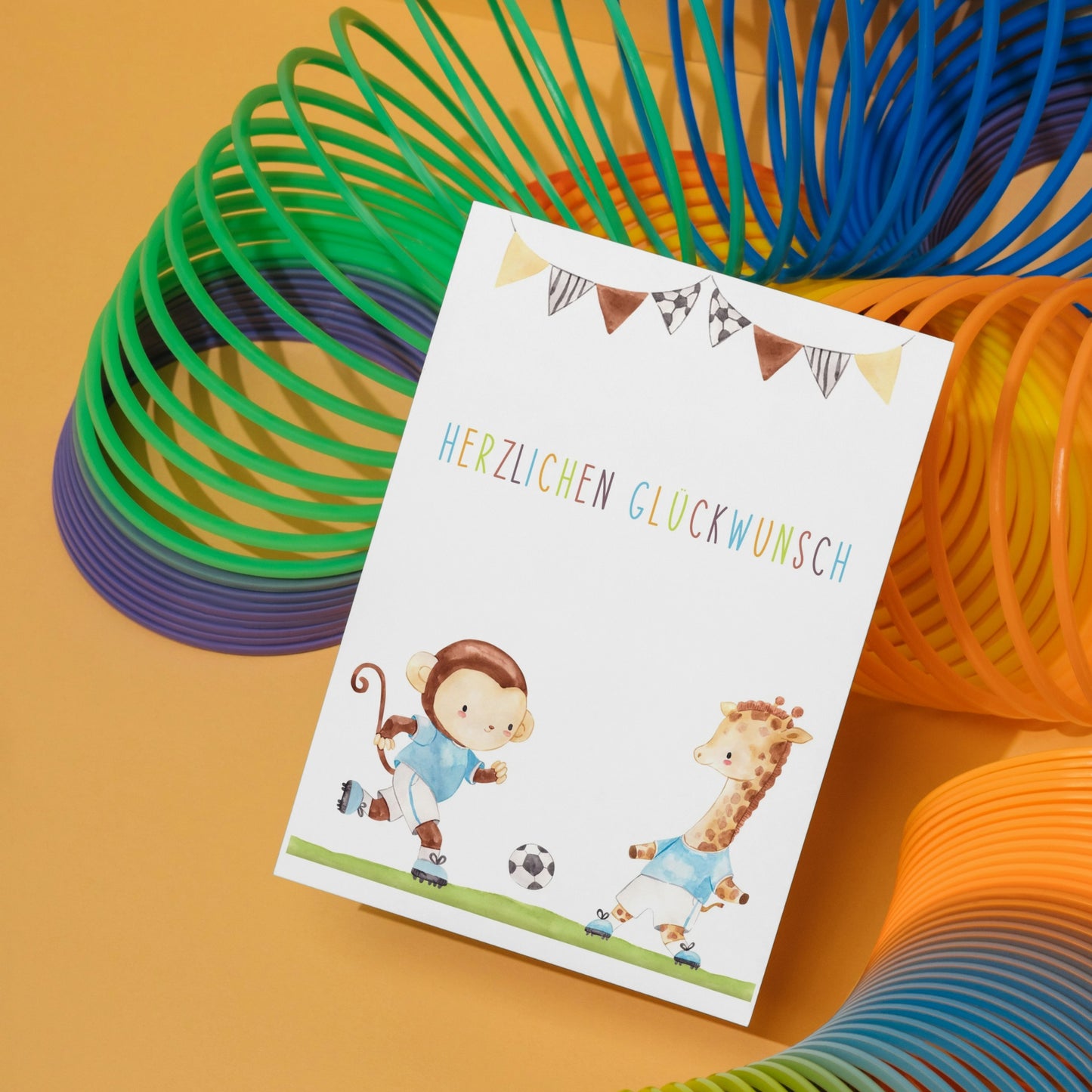 Karte Kindergeburtstag Fußball A6 mit handgemaltem Affen und Giraffe, die Fußball spielen, multicolor Herzlichen Glückwunsch-Schriftzug, auf hochwertigem Naturpapier gedruckt.