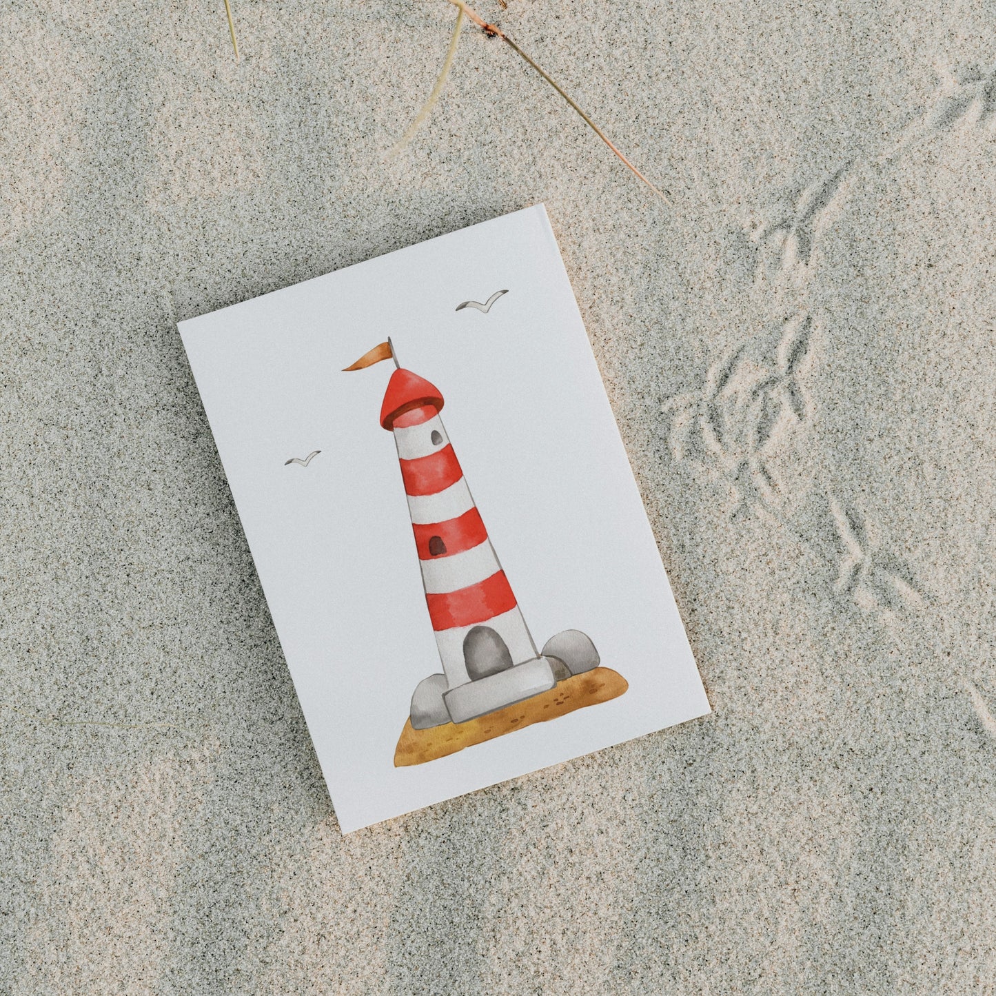 Postkarte Leuchtturm A6 auf Sand, zeigt einen rot-weiß gestreiften Leuchtturm mit Möwen. Gedruckt auf stabilem 300g Naturpapier, ideal für maritime Grüße.