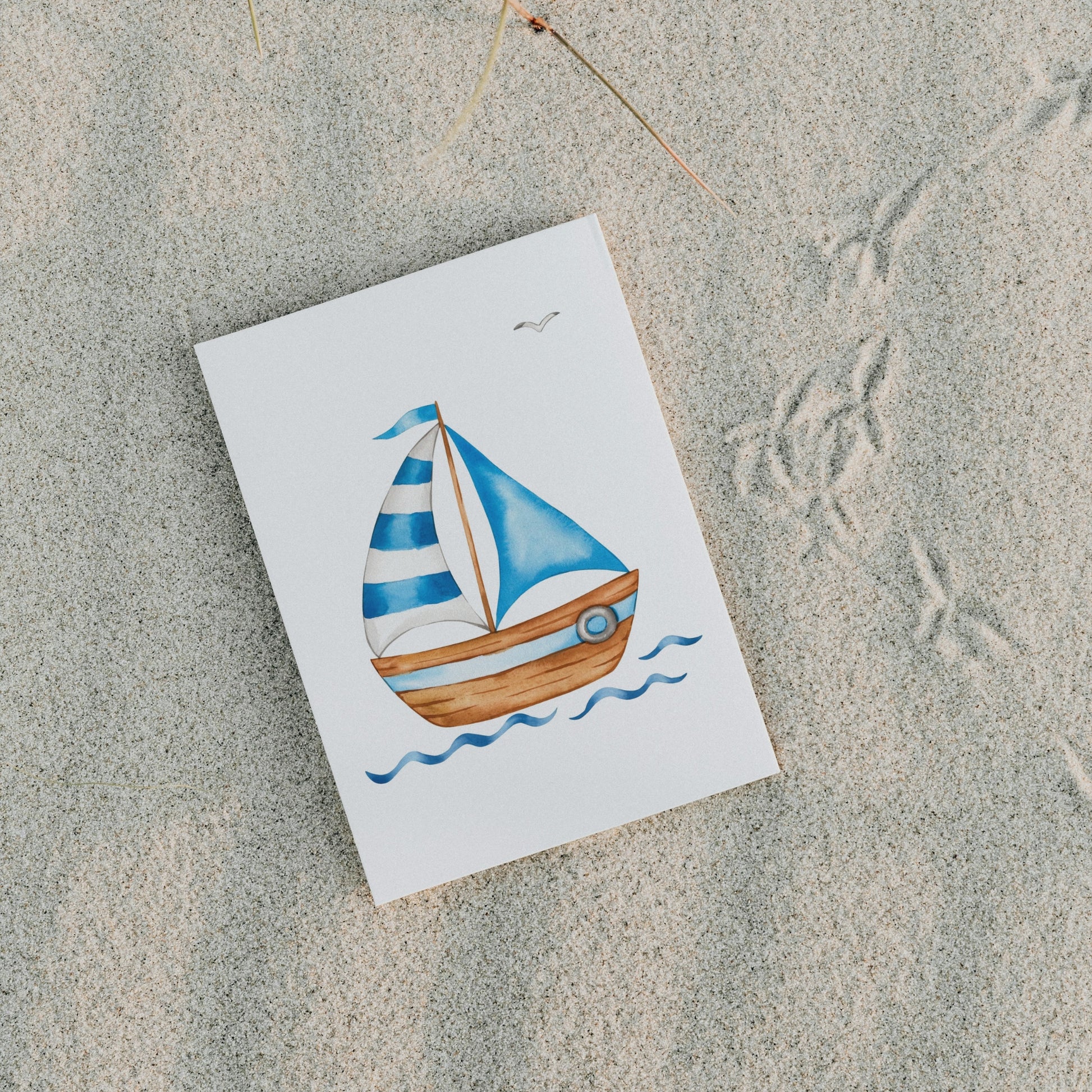 Postkarte Segelboot A6 zeigt ein illustriertes Segelboot mit blauen Segeln und Holzrumpf auf Sand, ideal für maritime Grüße und Dekoration.