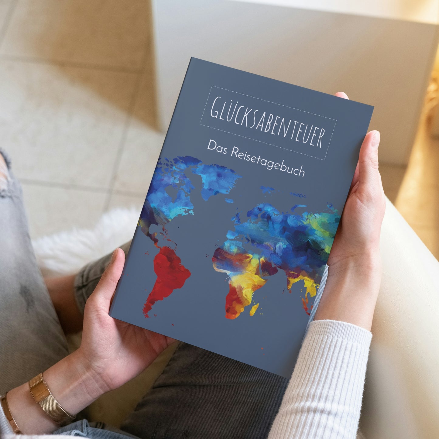Person hält Reisetagebuch A5 Softcover mit bunter Weltkarte. Ideal zum Planen und Festhalten von Reiseerinnerungen.