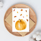 Postkarten-Set Herbstliebe 6 Karten A6, auf einem Holzuntergrund präsentiert, zeigt Aquarell-Kürbis und Blätter als herbstliches Motiv.