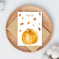 Postkarten-Set Herbstliebe 6 Karten A6: Karte mit Kürbis und Herbstlaub auf einem Teller und Umschlag.