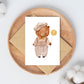 Karte Bär Vintage A6 zeigt einen cartoonartigen Bären mit Ballon auf einem Holzteller, ideal als handgemachte Gruß- oder Glückwunschkarte auf hochwertigem Naturpapier.