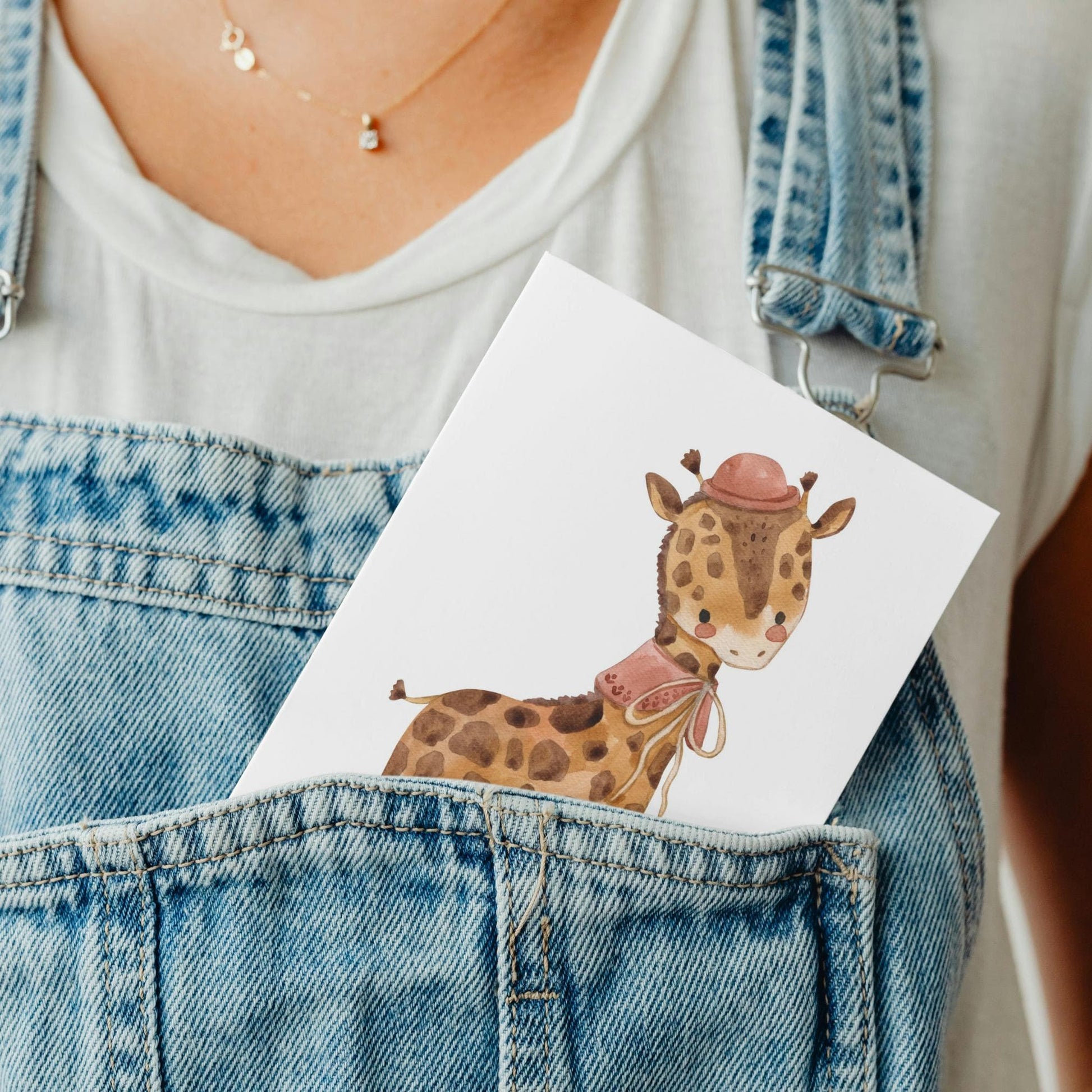 Karte Giraffe Vintage A6: Person hält Karte mit gezeichneter Giraffe im Hut im Overall-Tasche, passend als Gruß- oder Glückwunschkarte.