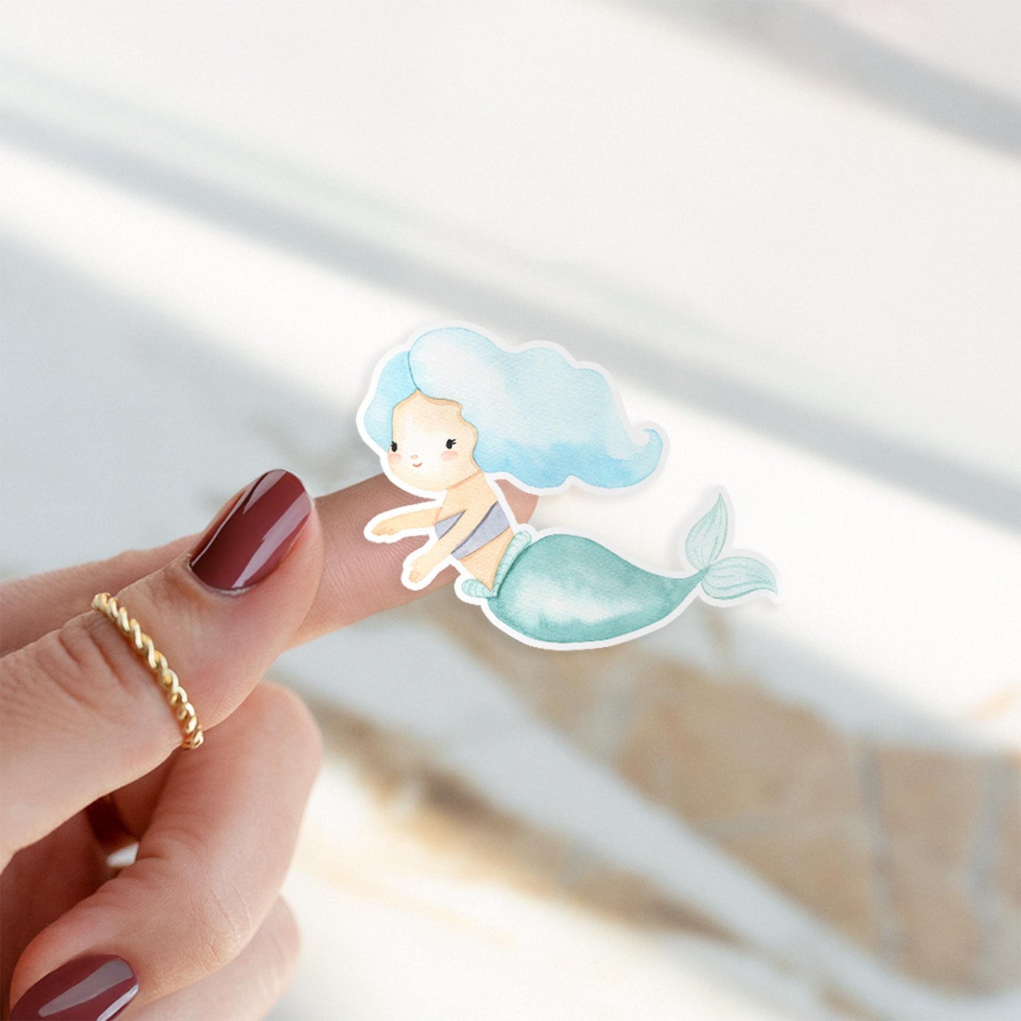 Finger mit einem handgemalten Sticker Meerjungfrau blau, gezeigt auf einem Fingernagel. Ideal für Bullet Journals oder Handyhüllen. Spritzfest und langlebig.