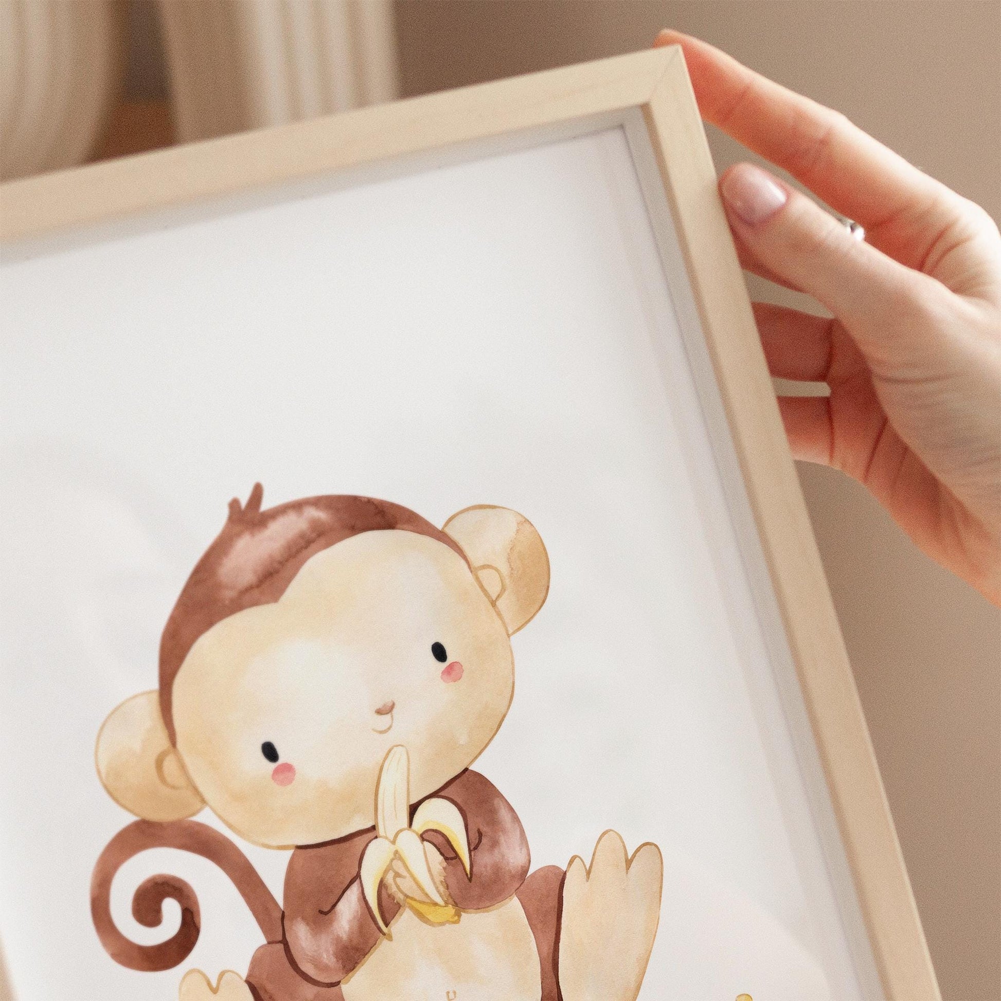 Poster Affe mit Banane A3 & A4: Hand hält ein Bild mit einem Cartoon-Affen, der eine Banane hält. Perfekte Kinderzimmerdeko aus hochwertigem Naturpapier.