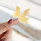 Sticker Dinosaurier fliegt: Ein gelber Dino-Sticker ruht auf einem Finger. Handgefertigt aus Vinyl, ideal für kreative Projekte und Dekorationen.