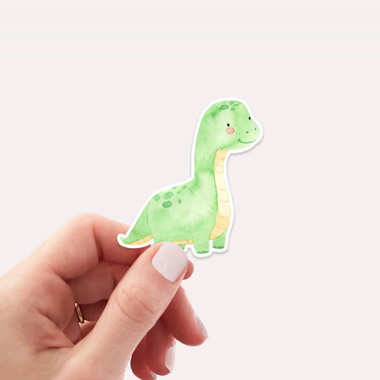 Ein Sticker Dinosaurier hellgrün wird von einer Hand gehalten, handgemalt auf hochwertigem Vinyl, ideal für Bullet Journals oder als individuelles Accessoire.