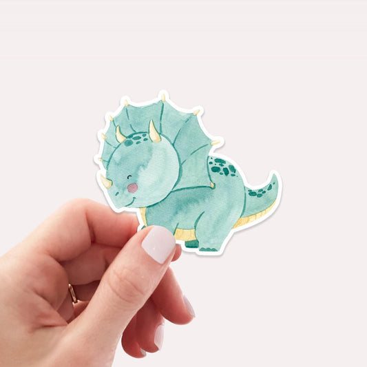 Sticker Dinosaurier Dreizack: Eine Hand hält einen handgemalten Vinyl-Dinosaurier-Sticker, ideal zum Dekorieren von Laptops oder Bullet Journals. Größe ca. 6 x 5 cm.