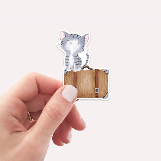 Sticker Katze & Koffer: Eine Hand hält einen handgemalten Katzen-Vinyl-Sticker, ideal für personalisierte Dekorationen und Reiseerinnerungen. Perfekt für Katzenliebhaber und Reisefans.