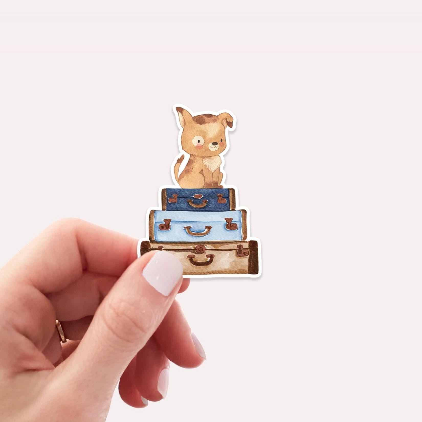 Hand hält Sticker Hund & Koffer, zeigt handgemalten Cartoon-Hund auf Gepäckstapel. Vinyl, spritzfest, ideal für Bullet Journals, Laptops, Handyhüllen.