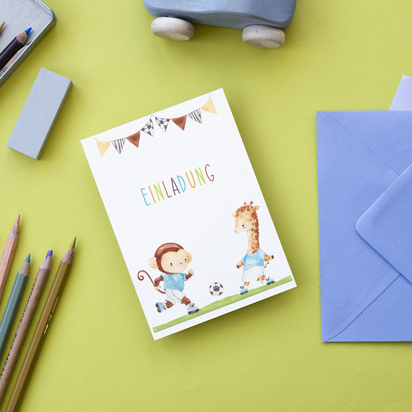 Einladung Kindergeburtstag Fußball A6 mit niedlichen Cartoon-Tieren und Fußballmotiv, inklusive passendem blauen Umschlag.
