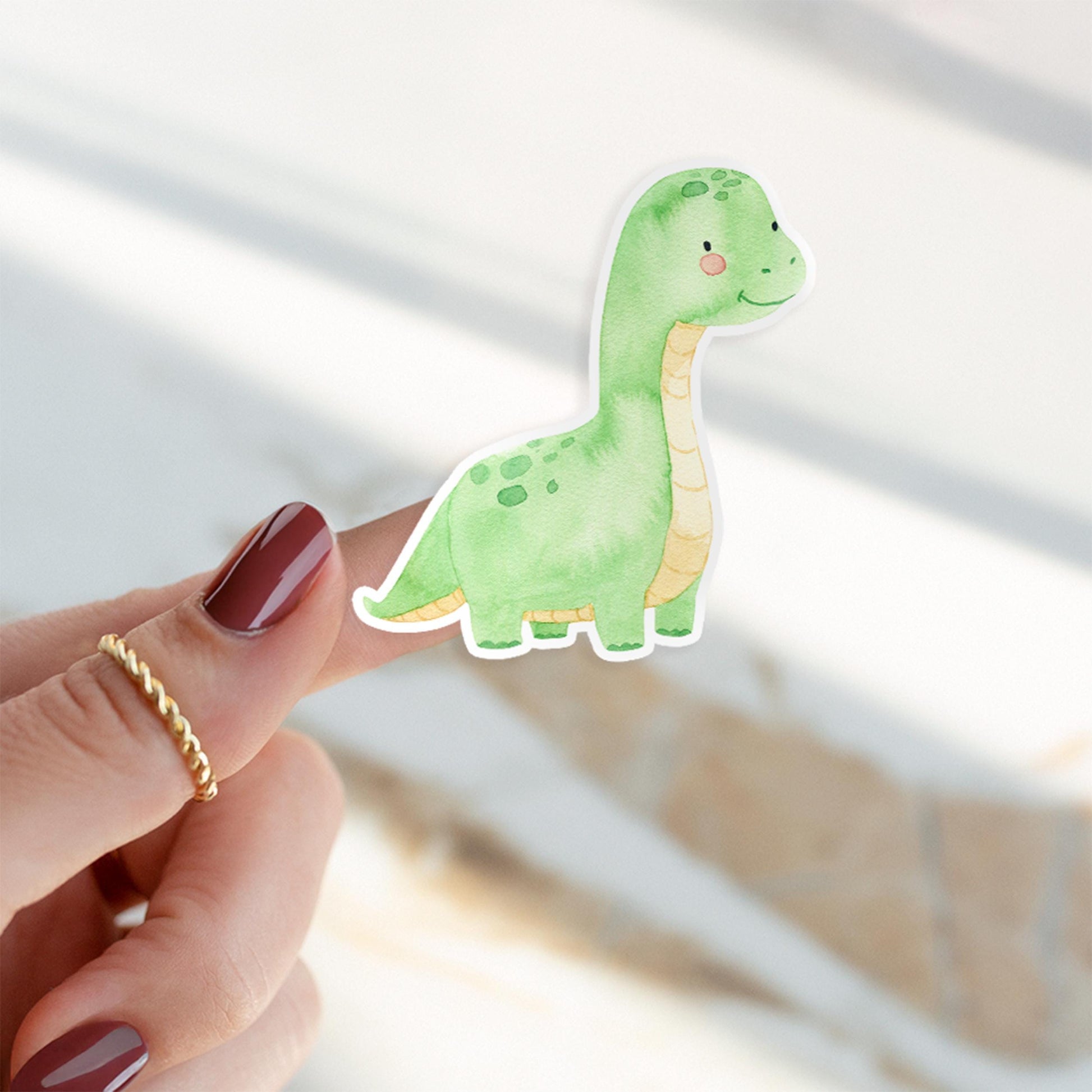 Person hält Sticker Dinosaurier hellgrün, handgefertigt aus hochwertigem Vinyl, ideal für Dekorationen und Bastelprojekte, spritzfest und langlebig.
