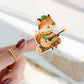 Sticker Fuchs & Gitarre: Nahaufnahme eines handgemalten Vinyl-Stickers zeigt einen Fuchs, der Gitarre spielt, von einer Hand gehalten. Ideal für kreative Dekorationen.