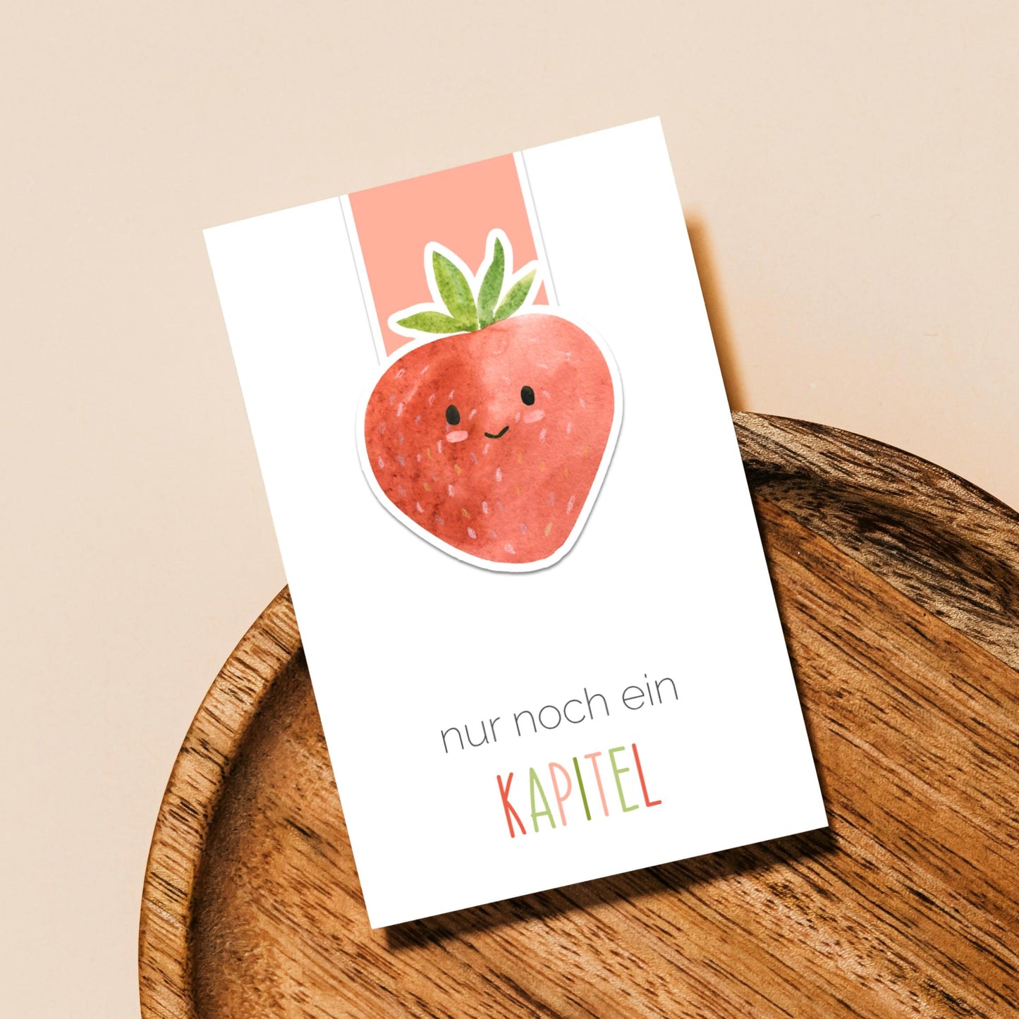 Magnetisches Lesezeichen Erdbeere auf Holztablett, zeigt eine lächelnde Erdbeere mit Text nur noch ein KAPITEL. Ideal für Buchliebhaber, handgemacht, robust und langlebig.
