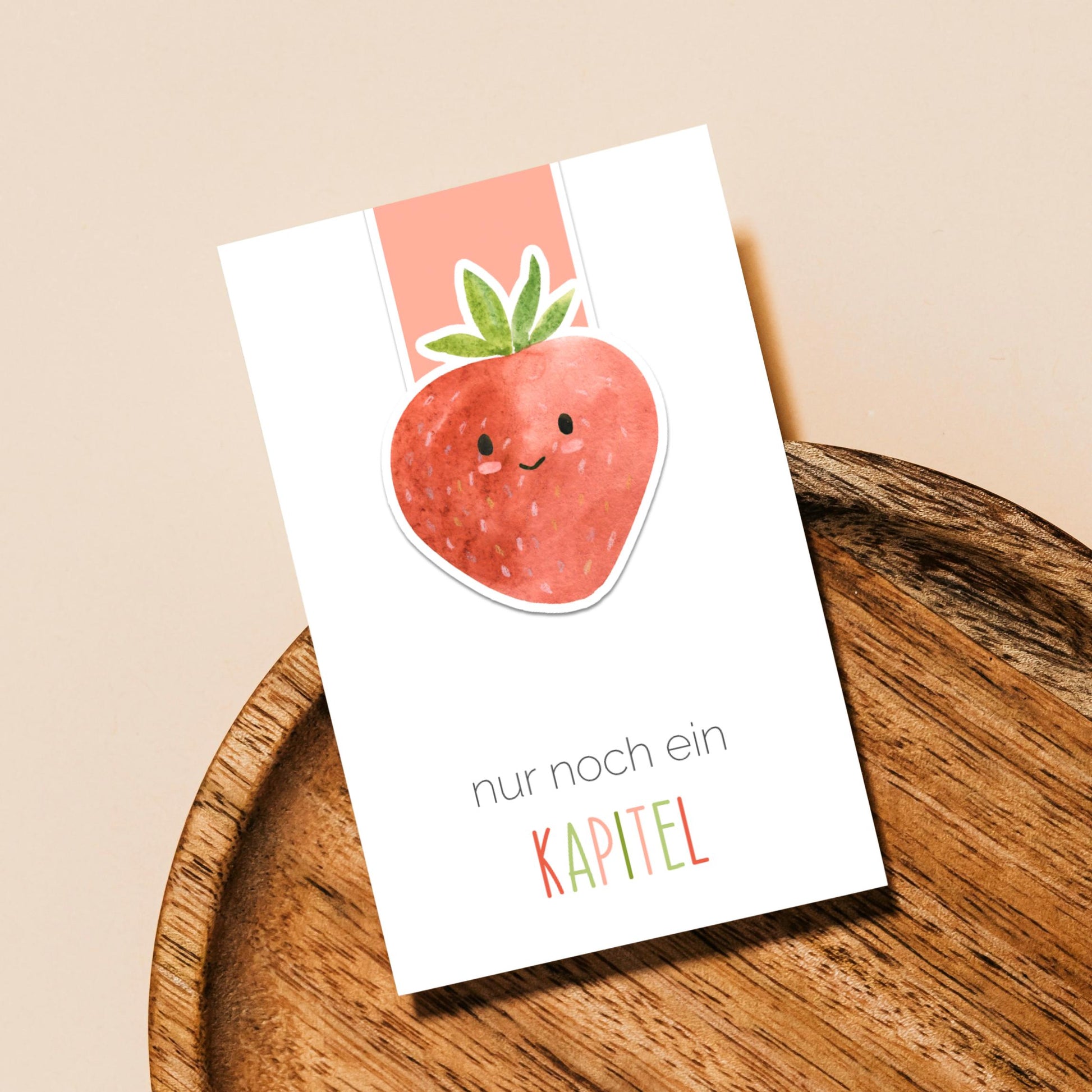 Magnetisches Lesezeichen Erdbeere auf Holztablett, zeigt eine lächelnde Erdbeere mit Text nur noch ein KAPITEL. Ideal für Buchliebhaber, handgemacht, robust und langlebig.