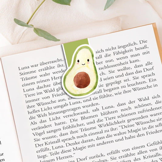 Magnetisches Lesezeichen Avocado: Handgemalte Avocado als Lesezeichen in einem deutschen Buch, umrahmt von grünen Blättern. Ideal für Buchliebhaber, 100% handgemacht.