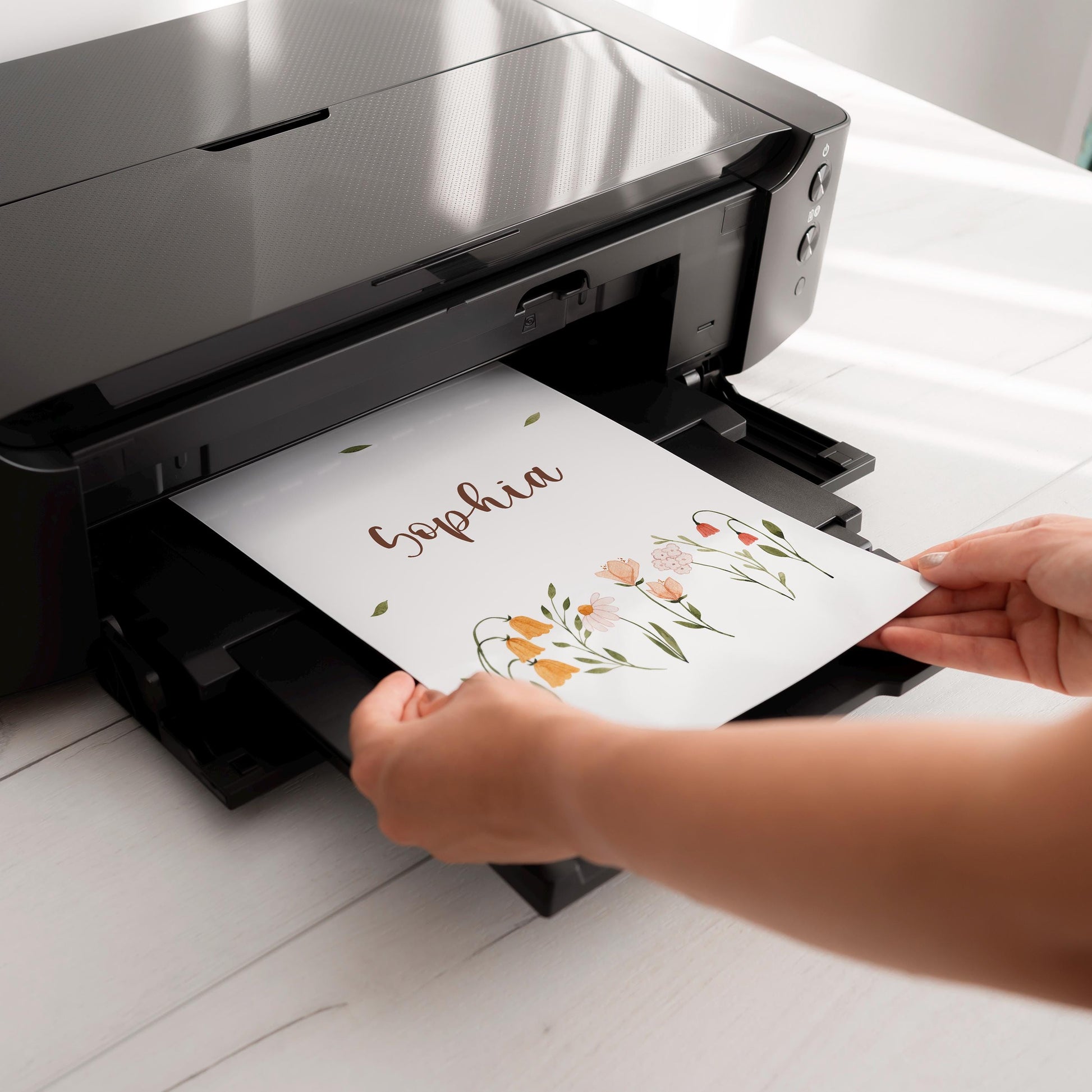 Ein Inkjet-Drucker druckt das personalisierte Namensposter Sophia mit zarten Wildblumen als Teil des 3er Sets Marienkäfer in A5, A4 und A3.