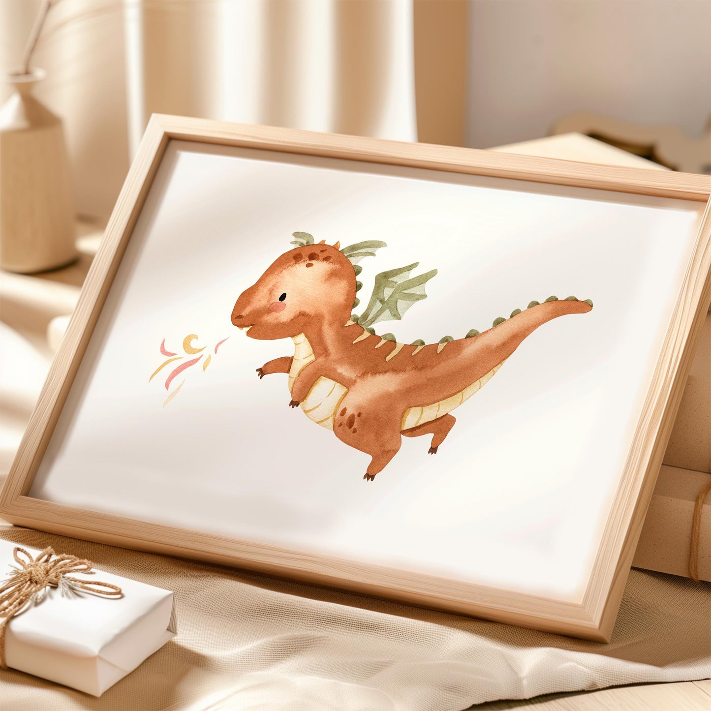 Poster Feuerdrache A3 & A4 in hellem Holzrahmen, zeigt kleinen Drachen mit grünlichen Flügeln und Flammen, auf neutralem Tuch neben Geschenkbox und Vase.