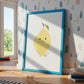 Namensposter Zitrone A3 & A4 mit lächelnder Zitrone im blauen Rahmen, gestützt an der Wand, neben Spielzeugzug und Kinderbüchern, ideal für Kinderzimmerdekoration.