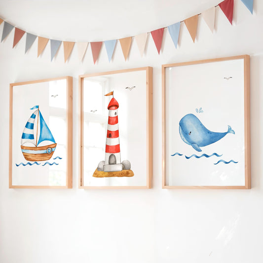 Posterset Boot Leuchtturm Wal A3 & A4: Drei Holzrahmenbilder zeigen ein Segelboot, einen Leuchtturm und einen Wal, mit pastellfarbenen Wimpeln darüber, an weißer Wand.