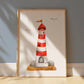 Leuchtturm Poster in Aquarellstil, gerahmt in hellem Holz. Zeigt rot-weiß gestreiften Leuchtturm mit orangefarbenem Wimpel, umkreist von stilisierten Möwen.